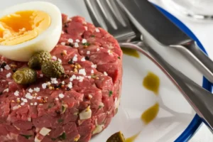 Classic steak tartare with raw egg yolk and garnish