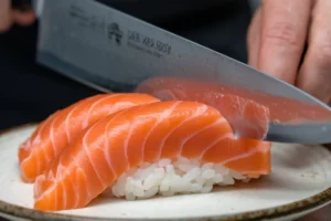 Raw salmon slices on a plate with lemon slices.