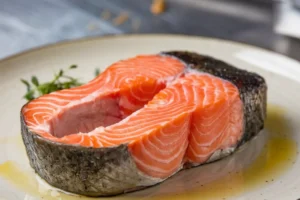 Sliced rare salmon with a pink center on a white plate.